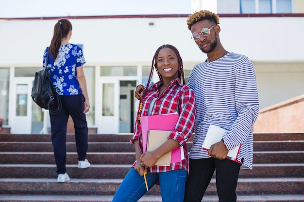 Delighted black students posing on stairs