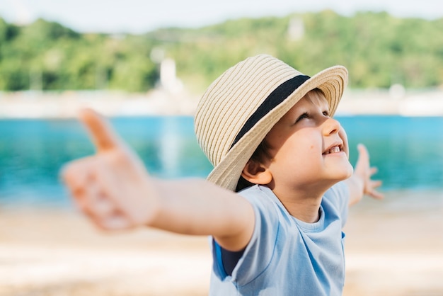 Delighted boy spreading hands and looking up in daylight