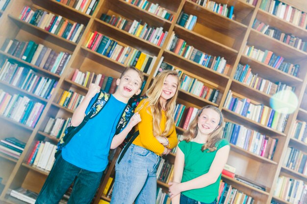 Free Photo delighted smiling children standing in school library 