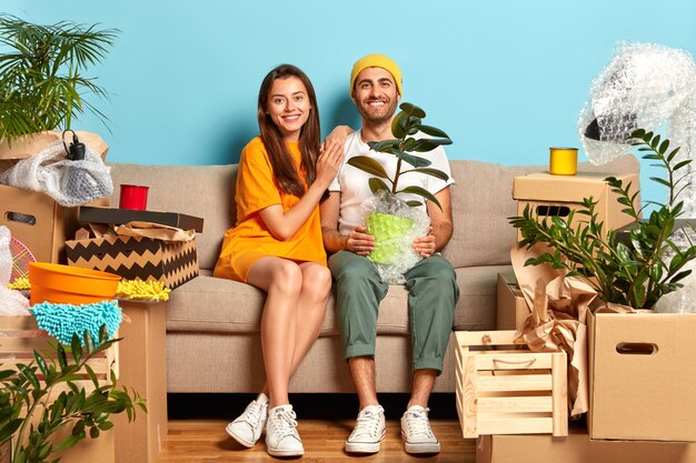 Delighted young couple sitting on the couch surrounded by boxes