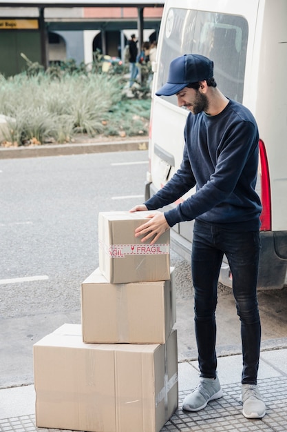 Deliver man looking at stacked cardboard boxes