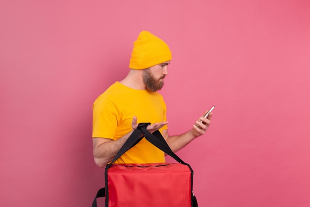 Free photo delivering food indignantly displeased looking at the phone on pink