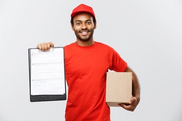 Free Photo delivery concept - portrait of handsome african american delivery man or courier showing a confirmation document form to sign. isolated on grey studio background. copy space.