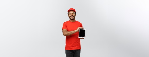 Delivery Concept Portrait of Handsome African American delivery man or courier showing tablet on you to check the order Isolated on Grey studio Background Copy Space