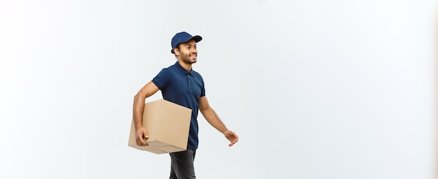 Delivery Concept Portrait of Happy African American delivery man in blue cloth walking to send a box package to customer Isolated on Grey studio Background Copy Space