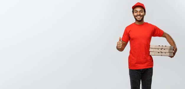 Delivery Concept Portrait of Happy African American delivery man holding box packages and showing thumps up Isolated on Grey studio Background Copy Space