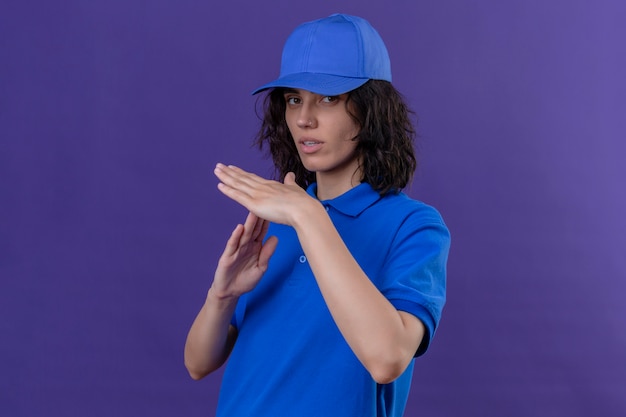 Free Photo delivery girl in blue uniform and cap looking onworked making time out gesture with hands on isolated purple