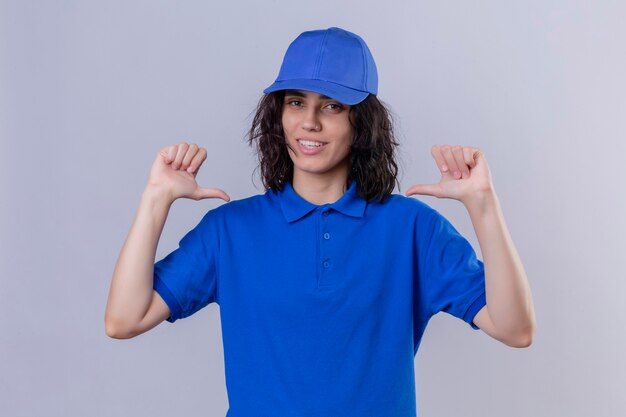 Delivery girl in blue uniform and cap pointing at herself looking confident smiling self-satisfied and proud standing 