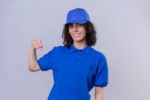 Delivery girl in blue uniform and cap  smiling friendly gesturing fist bump as if greeting approving or as sign of respect standing over isolated white space