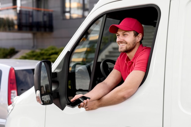 Free photo delivery man in car with mobile