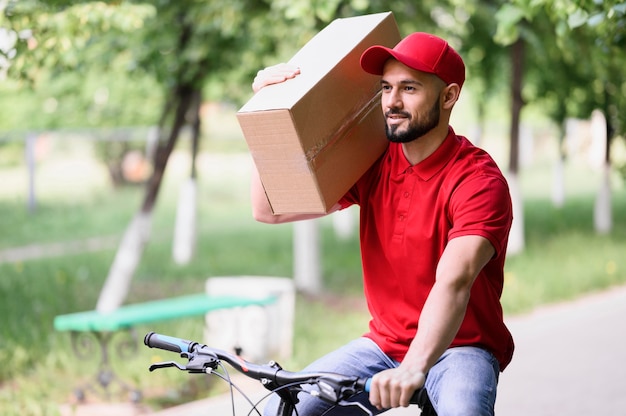 Free photo delivery man carrying box on a bike