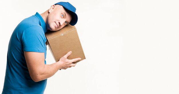 Delivery man posing while listening to cardboard box