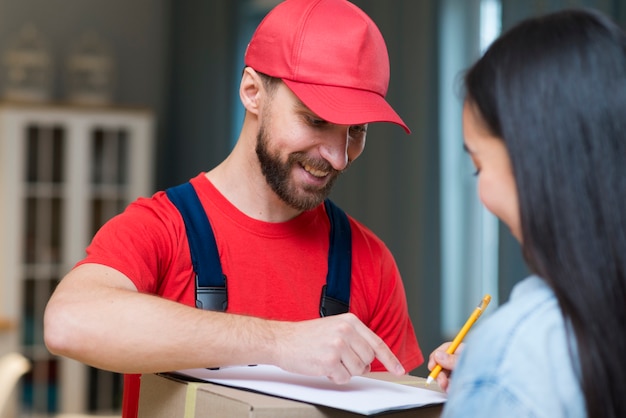 Delivery man showing woman where to sign to receive order