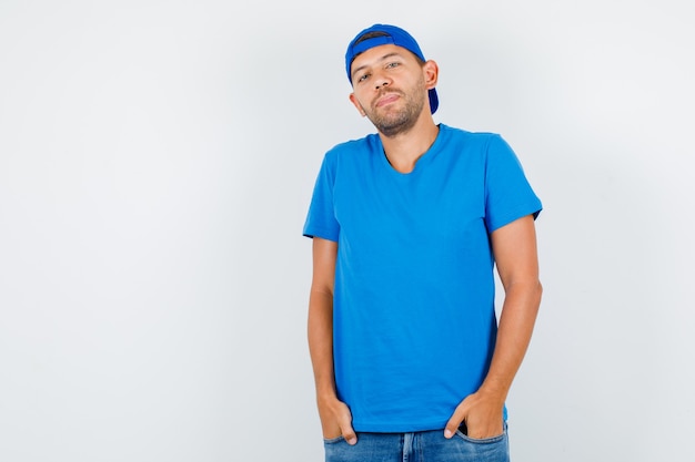 Free photo delivery man standing with hands in pockets in blue t-shirt