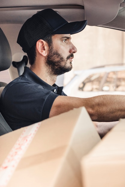 Free Photo delivery man with cardboard boxes driving vehicle