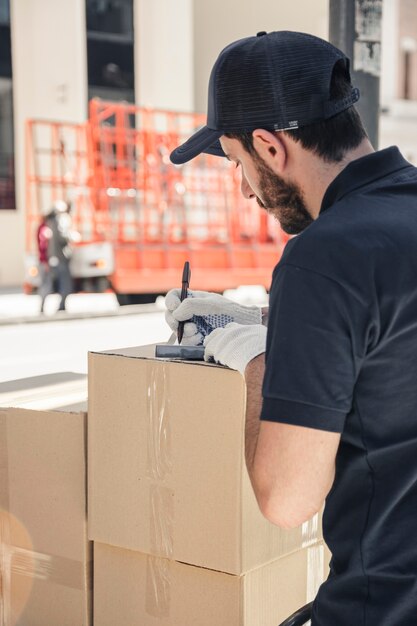 Delivery man with cardboard boxes writing on clipboard