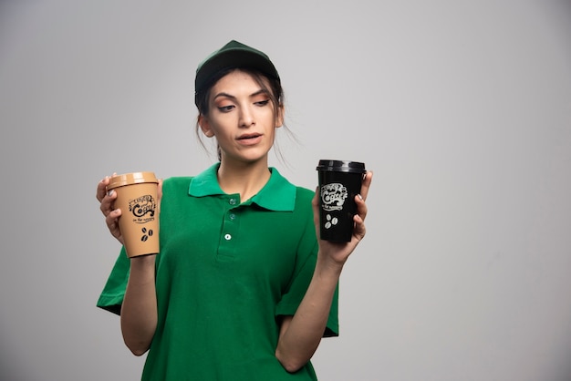 Free Photo delivery woman in green uniform posing with delicious coffee. 