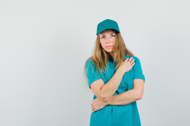 Delivery woman in t-shirt, cap holding hand on chest 