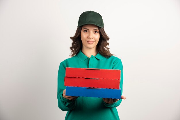 Delivery woman with pizza boxes posing on white.