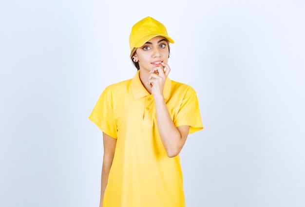 Delivery woman in yellow uniform standing and looking at camera.