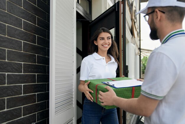 Deliveryman giving gift box and folder to woman