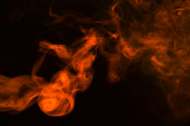 Free photo dense fumes of abstract orange smoke on dark background