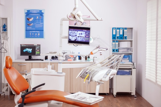 Free photo dental clinic interior with modern dentistry equipment in orange color. stomatology cabinet with nobody in it and orange equipment for oral treatment.