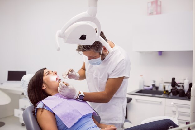 Dentist examining female patient teeth