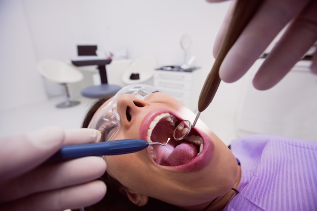 Dentist examining a female patient with tools