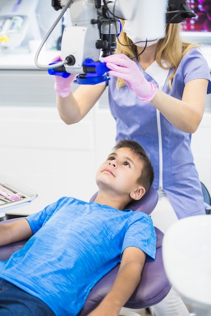 Dentist examining teeth of a boy through microscope