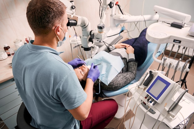 Dentist examining woman teeth with diagnostic microscope