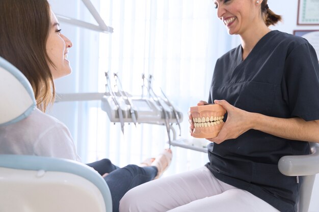 Dentist explaining patient about teeth model in clinic