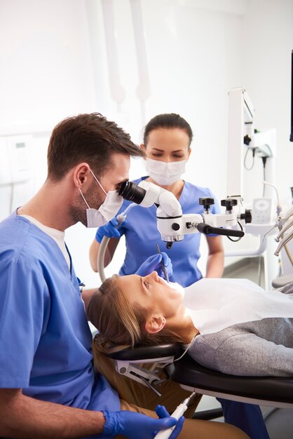 Dentist and his assistant working with dental microscope