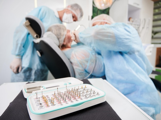 Free photo dentist and his assistant working with a patient in a dentist chair in dentist office