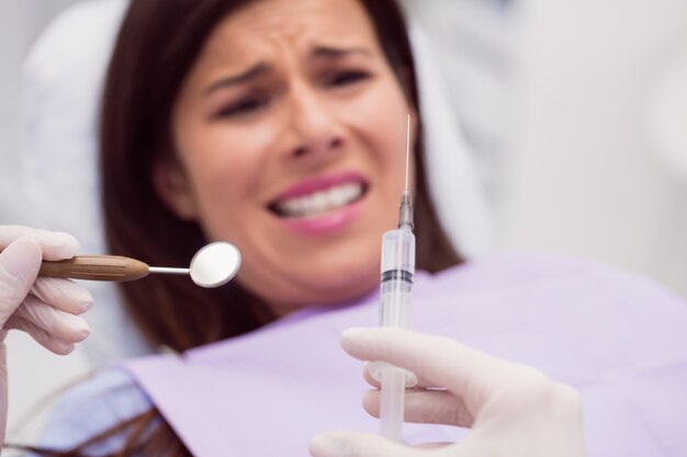 Dentist holding a syringe in front of scared patient