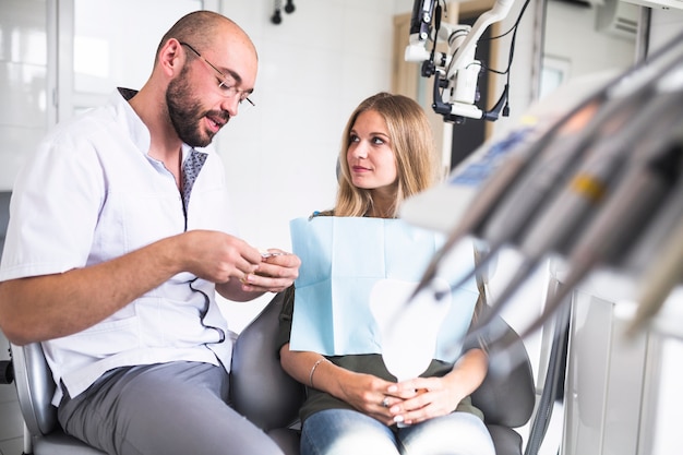 Free photo dentist talking with female patient while working on dental jaw