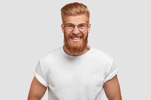 Free photo depressed angry irritated man model with ginger thick beard, strong muscular body, clenches teeth in annoyance