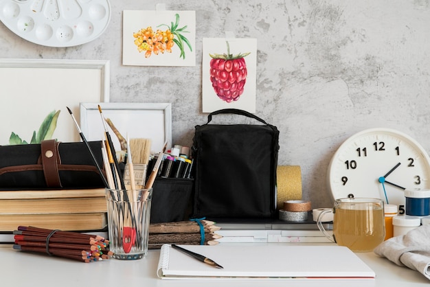 Free Photo desk arrangement with brushes and clock