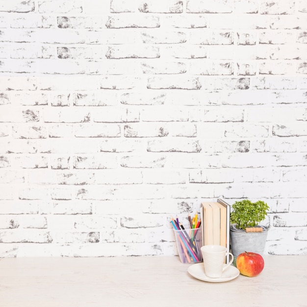 Free Photo desktop with books and cup near wall