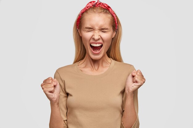 desperate blonde young woman posing against the white wall