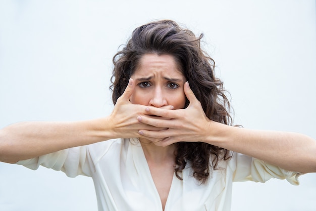 Desperate unhappy woman covering mouth with both hands