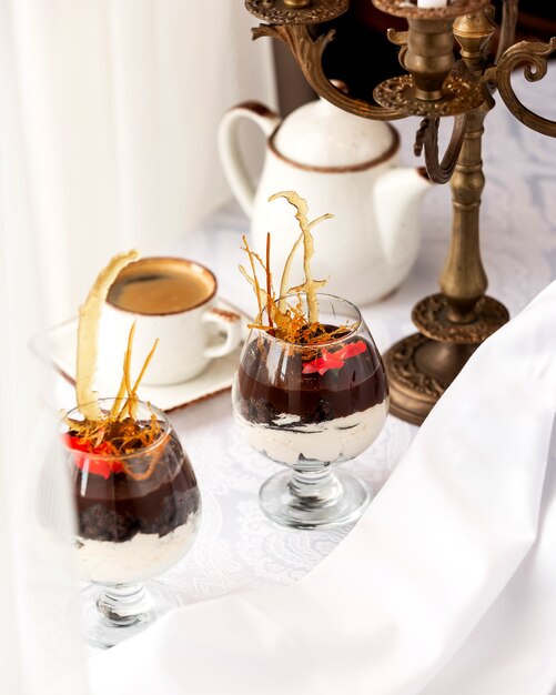 Desserts in glass with vanilla cream and chocolate sauce and espresso