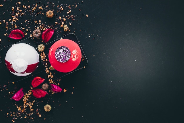 Desserts and rose petals on black background