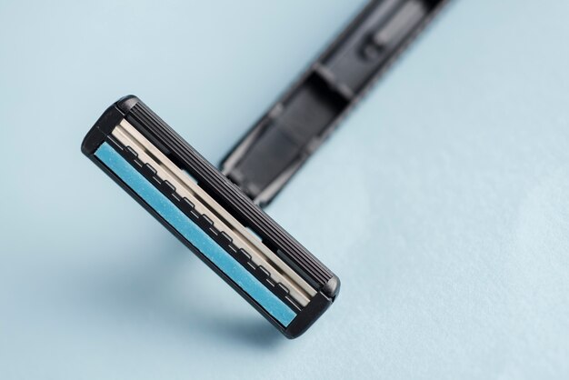 Detail of disposable black razor against blue backdrop