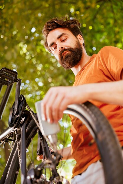 Detailed shot of modern bicycle chain being meticulously lubricated with grease for safe outdoor leisure. The image shows bike's disc brake ring being greased by male cyclist as summer maintenance