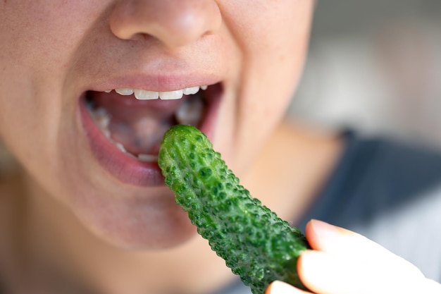 Free photo detailed shot of a woman eats fresh cucumber