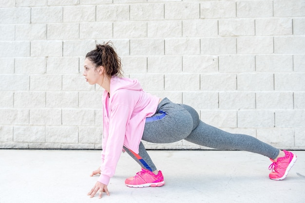 Free photo determined girl stretching legs near brick wall