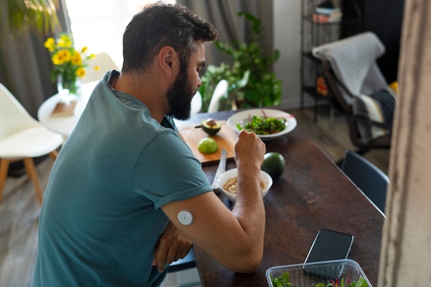 Free photo diabetic man with glucose patch sensor preparing meal