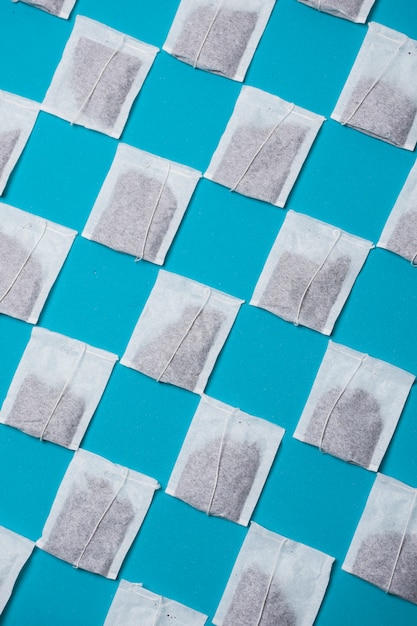 Diagonal closed white tea bags pattern on blue background