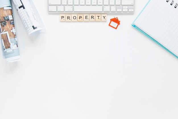 Diary and keyboard with blueprint on white backdrop